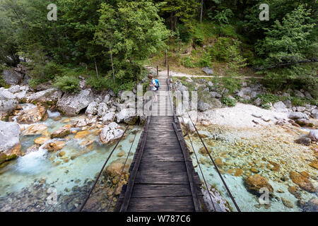 Jungen auf der Suche nach einem hölzernen Hängebrücke über schöne türkisblaue Fluss Soca während Trekking auf dem Trail, Bovec Soca, Slowenien, Europa Stockfoto