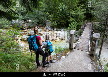 Mutter und Sohn über eine hölzerne Hängebrücke über schöne türkisblaue Fluss Soca während Trekking auf dem Trail, Bovec Soca, Slowenien, Europa Stockfoto