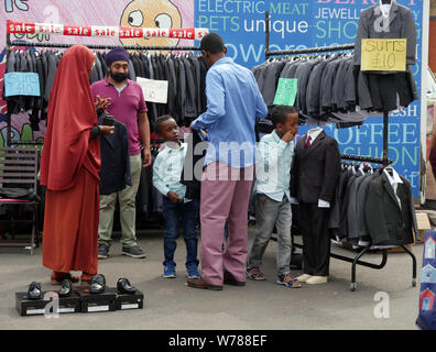 Familie Einkauf für die Jungen Anzüge auf einem Markt im Freien in England Großbritannien, ein Junge versucht, auf eine Jacke, während die Eltern einen Preis verhandeln. foto DON TONGE Stockfoto