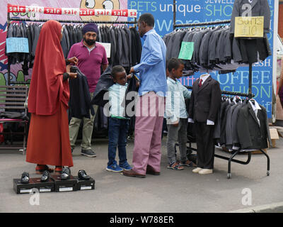 Familie Einkauf für die Jungen Anzüge auf einem Markt im Freien in England Großbritannien, ein Junge versucht, auf eine Jacke, während die Eltern einen Preis verhandeln. foto DON TONGE Stockfoto