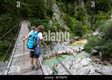 Süße junge Kreuzung eine hölzerne Hängebrücke über schöne türkisblaue Fluss Soca während Trekking auf dem Trail, Bovec Soca, Slowenien, Europa Stockfoto