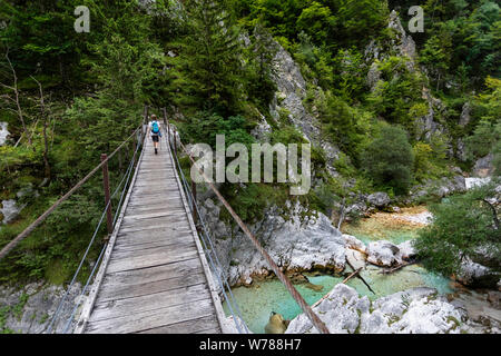 Süße junge Kreuzung eine hölzerne Hängebrücke über schöne türkisblaue Fluss Soca während Trekking auf dem Trail, Bovec Soca, Slowenien, Europa Stockfoto