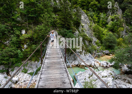 Süße junge Kreuzung eine hölzerne Hängebrücke über schöne türkisblaue Fluss Soca während Trekking auf dem Trail, Bovec Soca, Slowenien, Europa Stockfoto