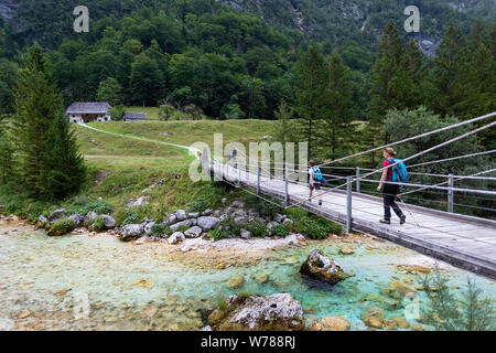 Mutter und Sohn über eine hölzerne Hängebrücke über schöne türkisblaue Fluss Soca während Trekking auf dem Trail, Bovec Soca, Slowenien, Europa Stockfoto