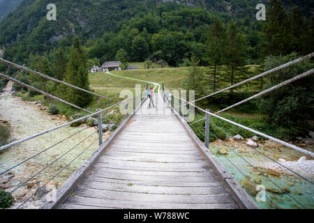 Mutter und Sohn über eine hölzerne Hängebrücke über schöne türkisblaue Fluss Soca während Trekking auf dem Trail, Bovec Soca, Slowenien, Europa Stockfoto