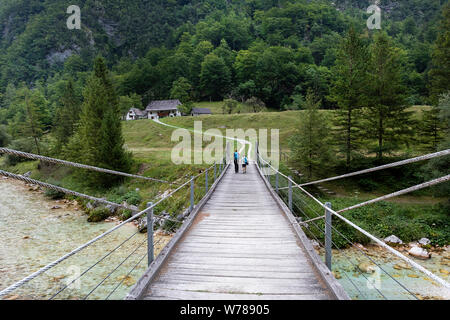 Mutter und Sohn über eine hölzerne Hängebrücke über schöne türkisblaue Fluss Soca während Trekking auf dem Trail, Bovec Soca, Slowenien, Europa Stockfoto