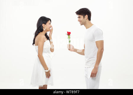 Mann, der der Frau eine Rose anbietet und lächelt Stockfoto