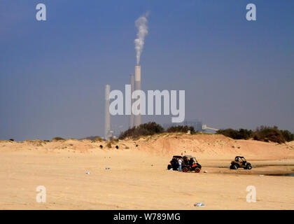 Dune Buggys auf zikim Strand an der Mittelmeerküste in Israel sitzen vor dem rutenberg Kraftwerk Schornsteinen. Stockfoto