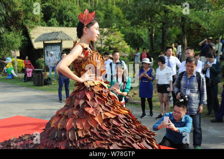 Chinesische Besucher machen Fotos von einem chinesischen Modell trägt ein zwei Meter langes Kleid aus Crepe myrthen Blätter an einem Blatt fashion show in Shampoola Wald Stockfoto