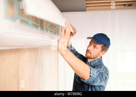 Junge Elektriker oder repiar Servicetechniker Öffnen der Abdeckung der Klimaanlage Stockfoto