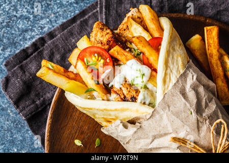 Gyros, Souvlaki Wraps in pita Brot mit Huhn, Kartoffeln und Tzatziki Sauce, blauer Hintergrund, Ansicht von oben. Stockfoto