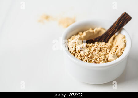 Superfoods Maca Pulver in einer weißen Schüssel auf einem weißen Hintergrund. Gesunde Ernährung Konzept. Stockfoto