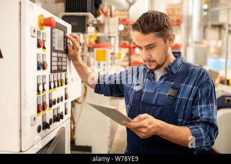 Junge factory Techniker suchen durch on-line-Anweisungen, die Sie von der Systemsteuerung Stockfoto