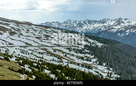 Spring Mountain - ein Panorama der Trail Ridge Road schlängelt sich durch auf der Seite der schneebedeckten Berge an einem stürmischen Frühling RMNP, Colorado, USA. Stockfoto