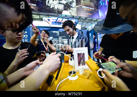 ---- Kolumbianische Modell Santiago Arenas Henao, Mitte und Besucher Spielen elektronischer Spiele am Stand von Cross Fire (CF) während des 15 China Digita Stockfoto