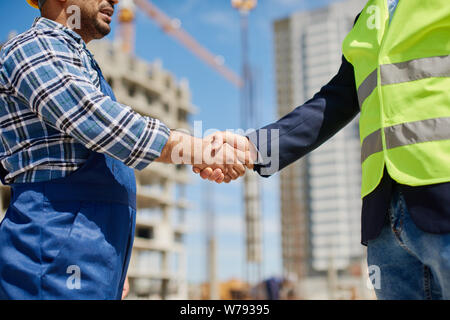 Zwei männliche Ingenieure jede andere Hände schütteln, freundlich. Stockfoto