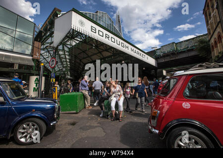 Street Scene am Borough Market in London, wo zwei Mini Cooper Kraftfahrzeuge vor dem Eingang zum Markt, England geparkt werden, Großbritannien Stockfoto