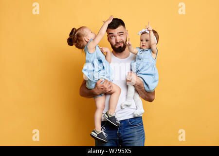 Hartnäckige laut childdren Necken theur älterer Bruder sitzend auf seinem Arme. Manipulation. Eltern und Kinder Konflikt. kleine Mädchen belästigt, da Stockfoto