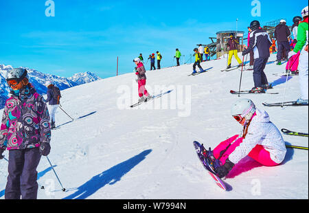 GOSAU, Österreich - 26. FEBRUAR 2019: Die Skifahrer bergab von der Oberseite der Zwieselalm Berg (Dachstein West) und junge Mädchen legt Bindungen von Sno Stockfoto