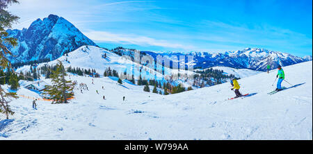 GOSAU, Österreich - 26. FEBRUAR 2019: Panorama der verschneiten Hügel der Zwieselalm Berg mit Ski laufen und Sportler, bergab mit Blick auf Dachste Stockfoto