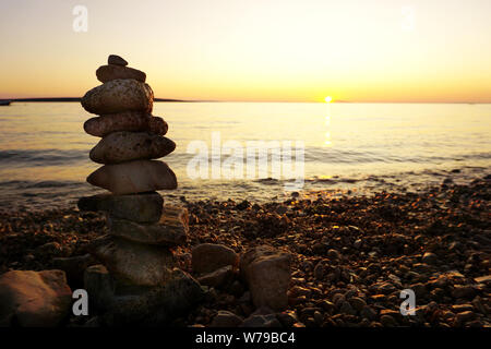 Hintergrund mit Stein ist in eine vertikale Linie auf der wunderschönen Kiesstrand bei Sonnenuntergang gestapelt, mit Kopie Raum Stockfoto