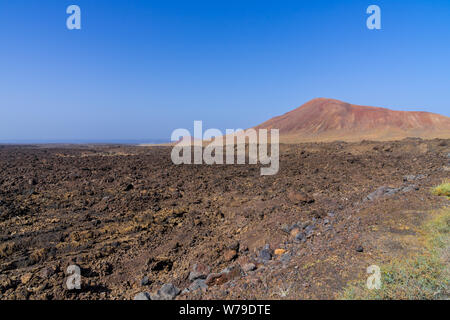 Spanien, Lanzarote, Roter Vulkan Berg hinter endlosen Lavafeld in der Nähe von Timanfaya Stockfoto