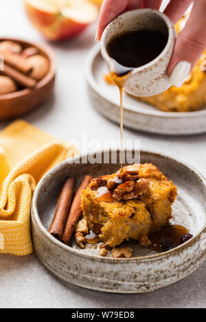 Gießen Ahornsirup auf Kürbis cake Slice. Herbst Komfort Essen. Pumpkin Pie spice mit Nussbaum und getrockneten Cranberry auf Platte Stockfoto