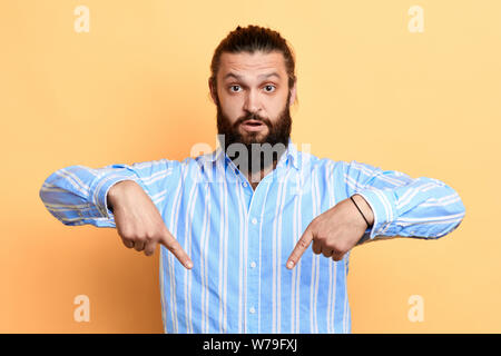 Younghandsome mann Punkt mit Index Finger nach unten, zufriedene neue Objekt inserieren, über Gelb Hintergrund isoliert, Dow, Platz für Text Stockfoto
