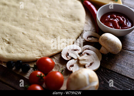 Nahaufnahme der gerollte Pizza Teig mit Cherry Tomaten, Champignons, Sauce und Chili Stockfoto