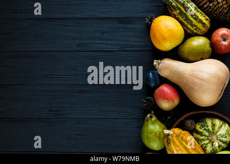 Kürbisse, Birnen, Pflaumen, Äpfel auf schwarzen Holztisch, Ansicht von oben, freier Platz für Text. Thanksgiving Day Zusammensetzung von Gemüse und Obst auf dunklen Woo Stockfoto