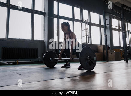 Auf den Erfolg konzentriert. Attraktive starke Muskulatur weibliche Bodybuilder tun heavy duty hockt Anheben barbell Am crossfit Fitnessraum Stockfoto