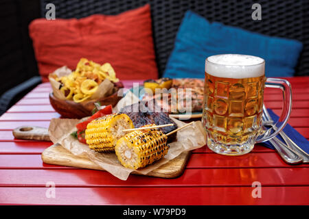 Gegrillter Mais und geräuchertem Rippchen mit Bier auf der Terrasse eines Restaurants Stockfoto