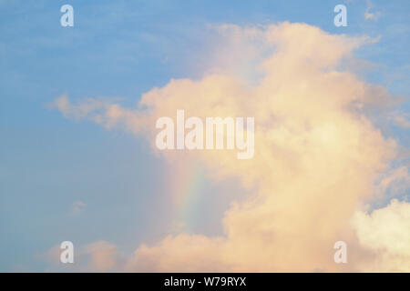 Rosa Wolken bei Sonnenuntergang mit einem Regenbogen. Stockfoto