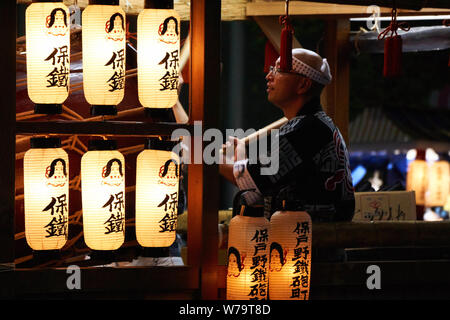 Ein Japaner spielt eine große Taiko drum während von traditionellen japanischen Laternen an der Akita Kanto Matsuri 2016 beleuchtet. Stockfoto