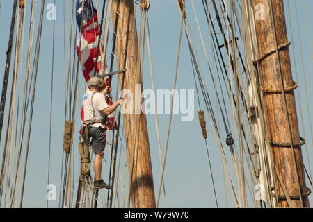 Ein männliches Mitglied der Besatzung der Pride of Baltimore II klettert die Takelage Teil der Mast des Tall Ship zu beheben. Stockfoto