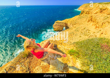 Backpacker Mädchen mit offenen Armen an der Natural Bridge im Kalbarri National Park, Western Australia. Glückliche Frau auf Klippen der Küste des Indischen Ozeans in Stockfoto