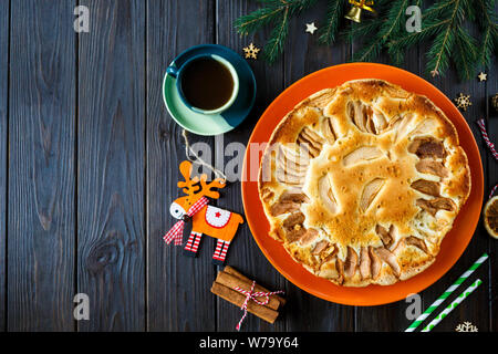 Früchtebrot für Weihnachten mit Äpfeln auf dem orange Teller dekoriert mit Tasse Kaffee auf dem hölzernen Tisch. Delicioius hausgemachtes Gebäck. Neues Jahr Stockfoto