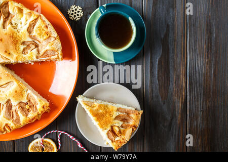 Früchtebrot für Weihnachten mit Äpfeln auf dem orange Teller dekoriert mit Tasse Kaffee auf dem hölzernen Tisch. Delicioius hausgemachtes Gebäck. Neues Jahr Stockfoto