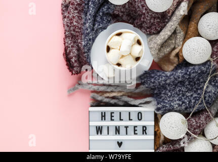 Warme, gemütliche winter Bekleidung, Schal, Lightbox und weihnachtsschmuck als Frame auf Pastell rosa Hintergrund. Weihnachten Konzept flach. Hallo Winter Stockfoto