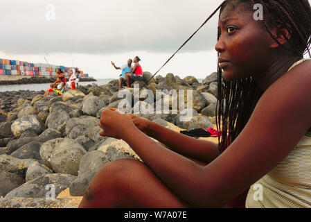 Strandtag und Menschen hängen an der Festung São Sebastião in São Tomé. Stockfoto