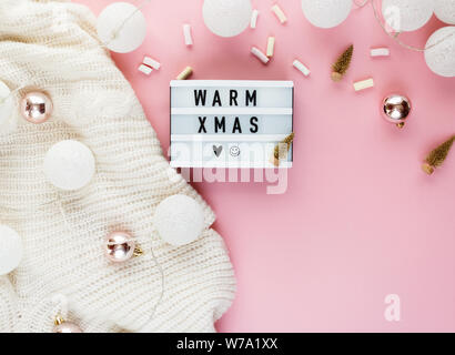 Warme, gemütliche winter Bekleidung, Lightbox und weihnachtsschmuck als Frame auf Pastell rosa Hintergrund. Weihnachten Konzept flach. warme Weihnachten Titel Stockfoto