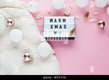 Warme, gemütliche winter Bekleidung, Lightbox und weihnachtsschmuck als Frame auf Pastell rosa Hintergrund. Weihnachten Konzept flach. warme Weihnachten Titel Stockfoto