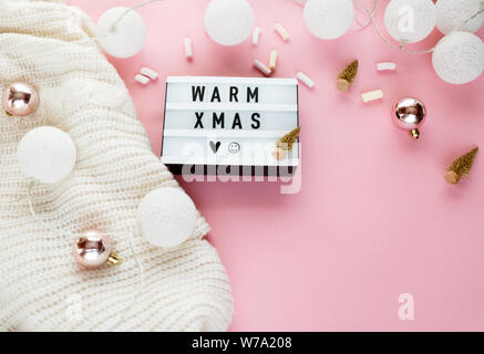 Warme, gemütliche winter Bekleidung, Lightbox und weihnachtsschmuck als Frame auf Pastell rosa Hintergrund. Weihnachten Konzept flach. warme Weihnachten Titel Stockfoto