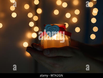 Zicklein hält Weihnachten Laterne in der Hand und leuchtet bokeh Hintergrund. Neues Jahr feier Konzept, festliche Stimmung Stockfoto