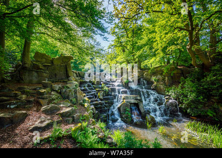 Der künstliche Wasserfall Kaskade in Virginia Water Lake, Windsor Great Park, Berkshire, South East England an einem sonnigen Frühlingstag Stockfoto