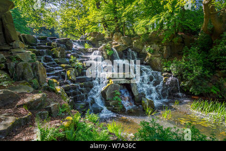 Der künstliche Wasserfall Kaskade in Virginia Water Lake, Windsor Great Park, Berkshire, South East England an einem sonnigen Frühlingstag Stockfoto