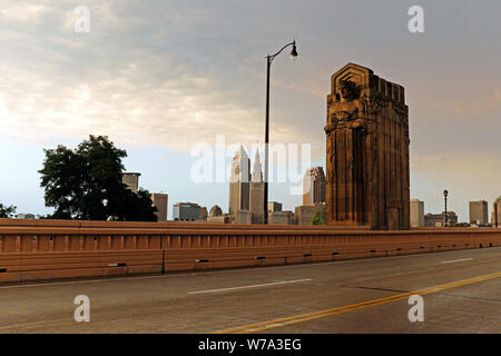 Die Skyline der Innenstadt von der Hope Memorial Bridge aus, wo sich einer der Art déco-Wächter des Verkehrs über der Straße in Cleveland, Ohio, erhebt. Stockfoto