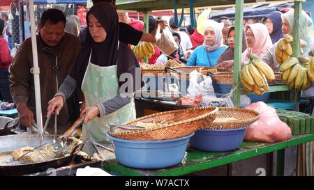 Jakarta, Indonesien - August 2019: Eine muslimische Frau sind braten Bananen zu verkaufen, während die Käufer warten. Stockfoto