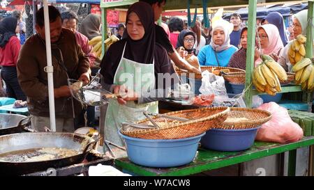 Jakarta, Indonesien - August 2019: Eine muslimische Frau sind braten Bananen zu verkaufen, während die Käufer warten. Stockfoto