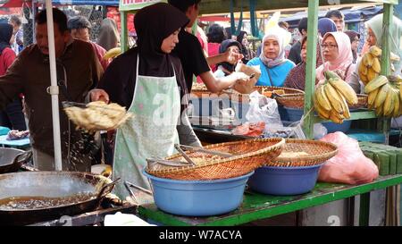 Jakarta, Indonesien - August 2019: Eine muslimische Frau sind braten Bananen zu verkaufen, während die Käufer warten. Stockfoto